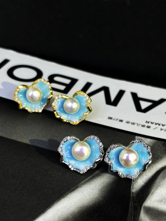 A pair of glacier blue enamel stud earrings featuring 8mm natural freshwater pearls and sterling silver posts.