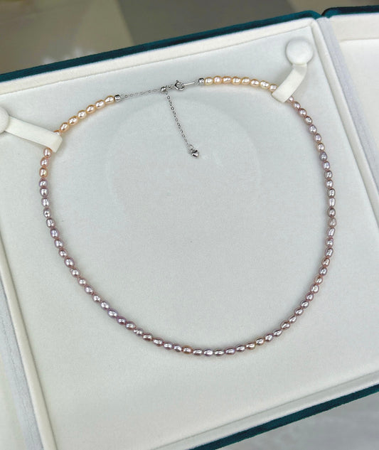 Gradient necklace featuring 3–4mm freshwater pearls fading from orange to purple, with sterling silver adjustable clasp.