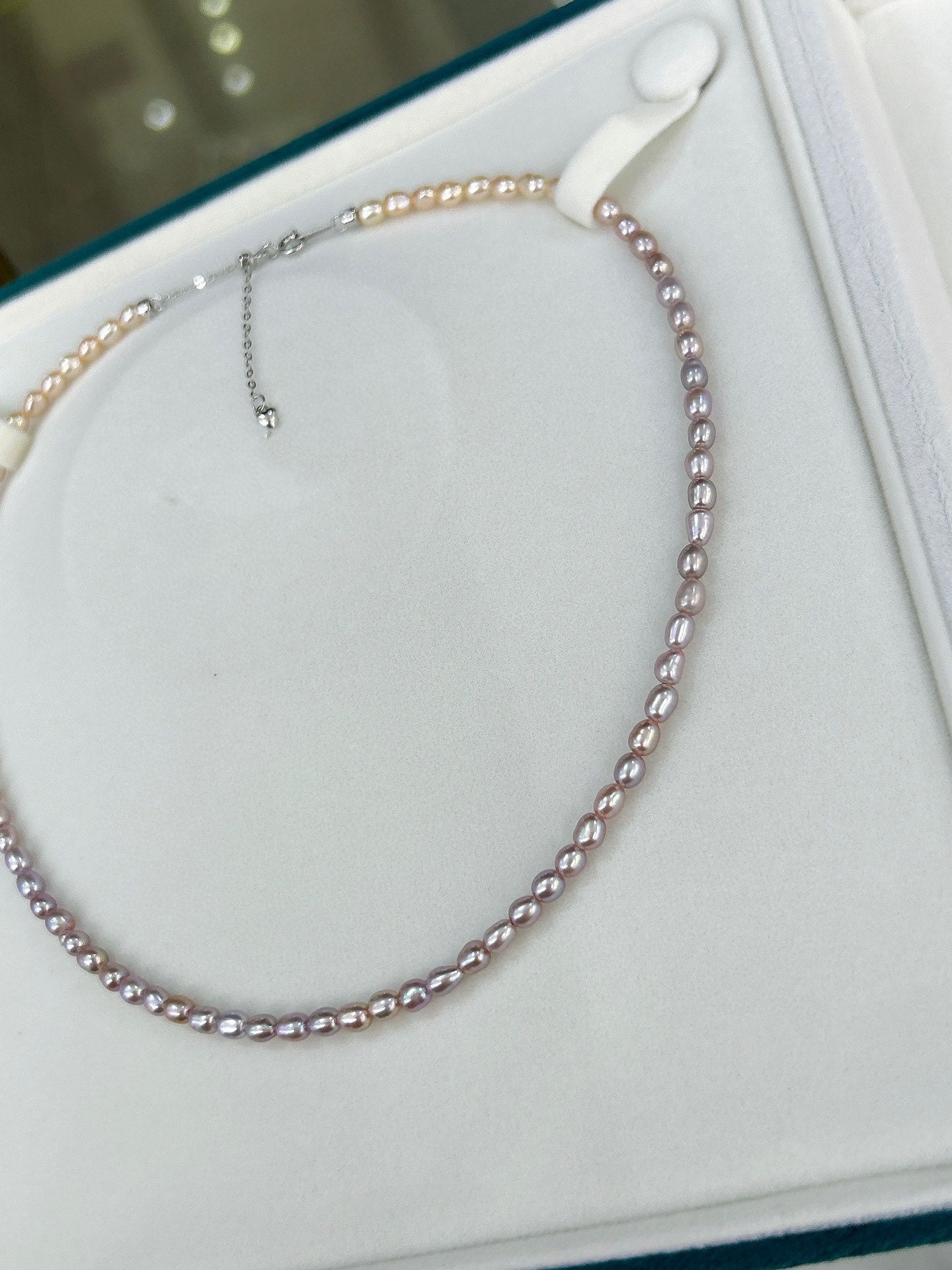 Gradient necklace featuring 3–4mm freshwater pearls fading from orange to purple, with sterling silver adjustable clasp.