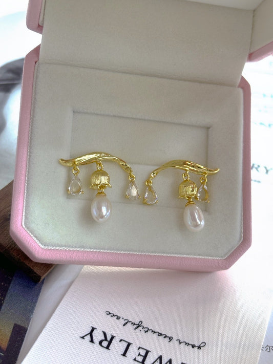 A pair of Chinese-inspired lily-of-the-valley pearl earrings featuring dangling freshwater pearls and intricate silver floral design.