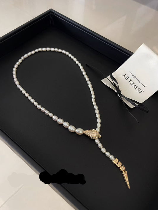 Elegant snake-inspired pearl necklace with cubic zirconia and gradient freshwater pearls.