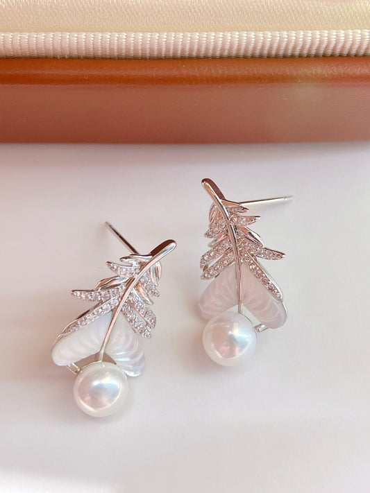Close-up of feather-inspired pearl earrings
Pearl stud with feather detail and mother-of-pearl finish