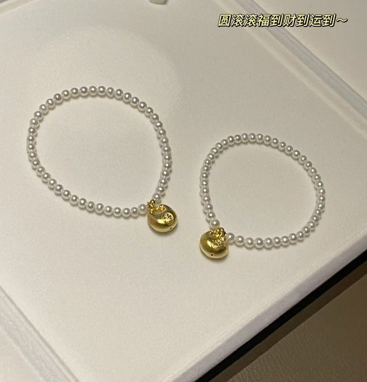 Lucky gold charm pearl bracelet with 3-4mm freshwater pearls and a fortune pouch bead on stretch cord, approx. 17cm length