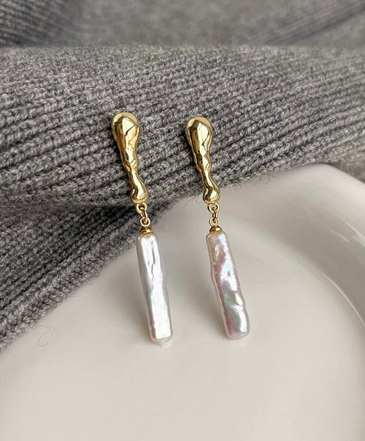 Long baroque pearl drop earrings with asymmetrical design on white background