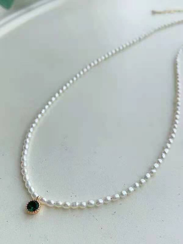 Close-up of seed pearl strand with single green crystal detail