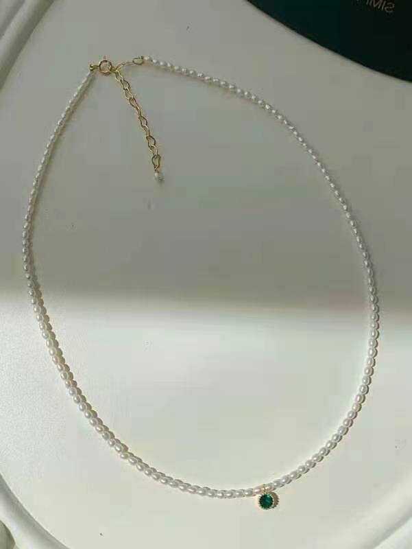 Close-up of seed pearl strand with single green crystal detail