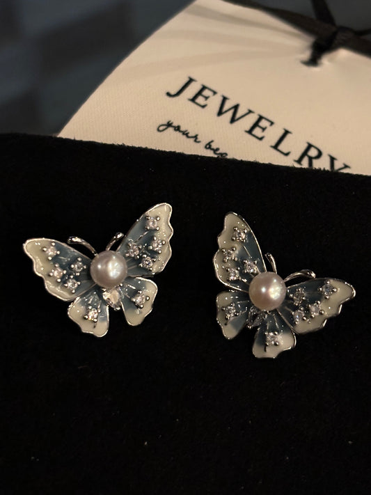 Blue enamel butterfly pearl stud earrings on white background