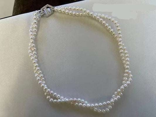 Double-layer pearl choker with gold and zircon clasp on white background