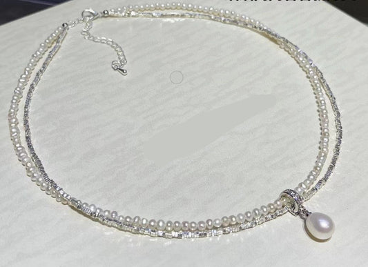 Double-layer sterling silver necklace with baby pearls and teardrop pearl on white background