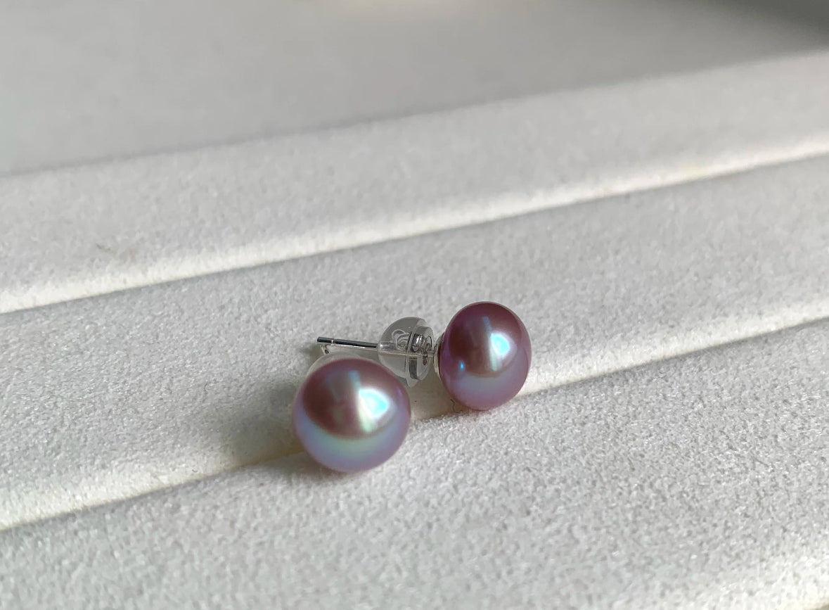 Close-up of 8–9mm lavender freshwater button pearl stud earrings on a white velvet tray