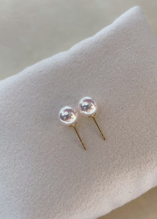 Close-up of luminous Akoya pearl stud earrings set in 18K gold