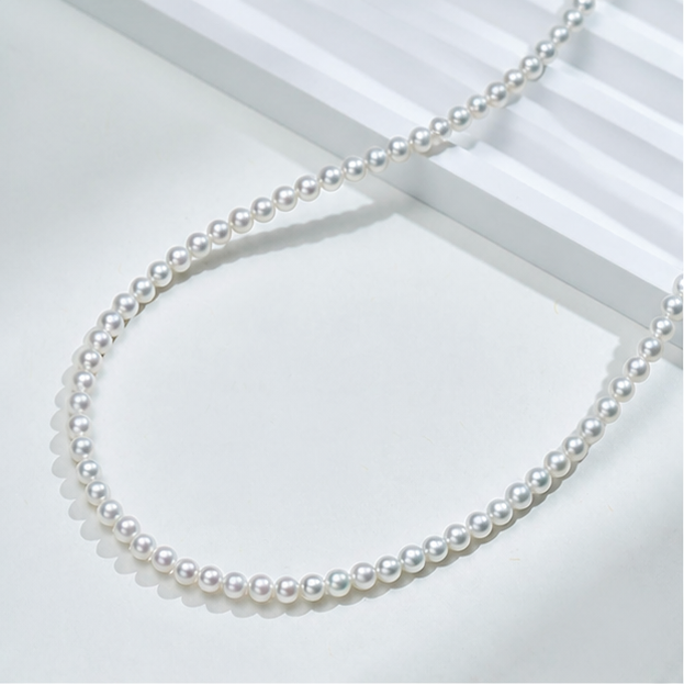 Dainty baby freshwater pearl necklace arranged on pearl-grey silk