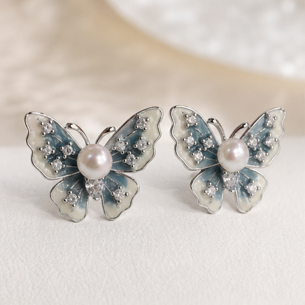 Blue Ice Enamel Butterfly Pearl Stud Earrings – Freshwater & Sterling Silver photographed on ivory satin